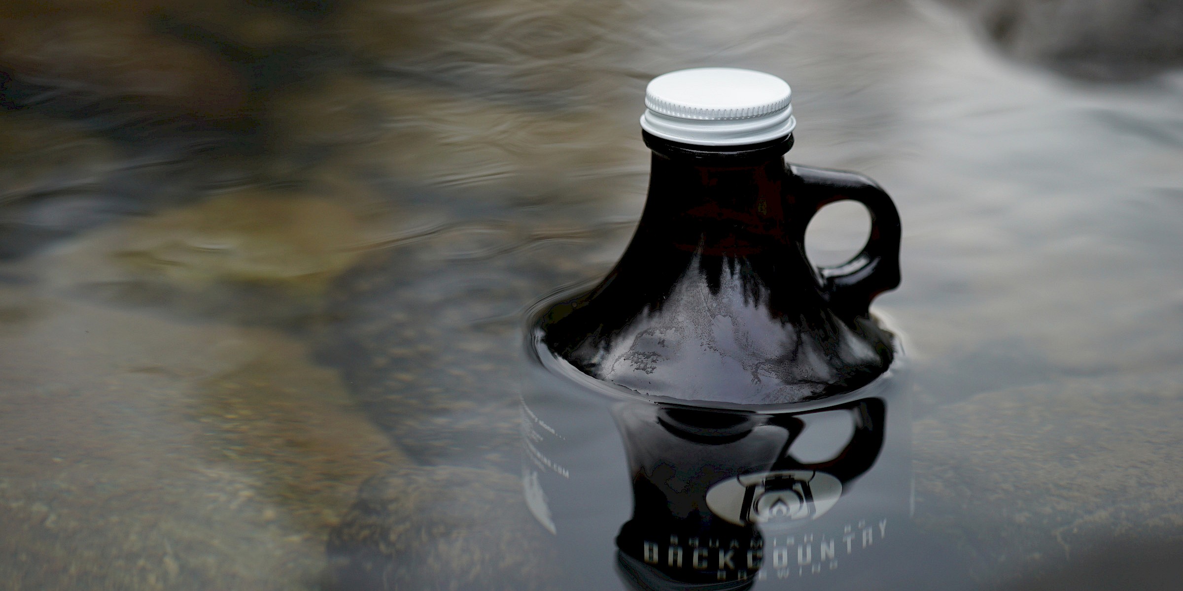 Backcountry Brewing Growler cooling in a clear stream