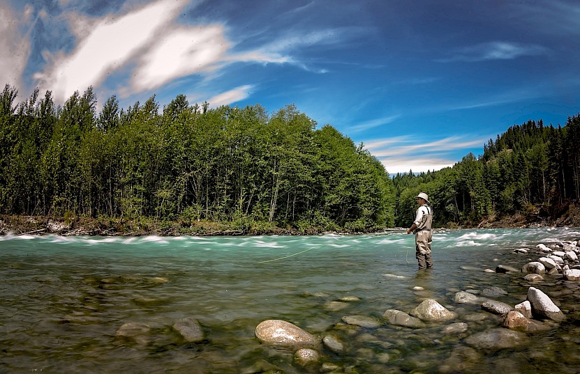 Man fly fishing in a river on a sunny day