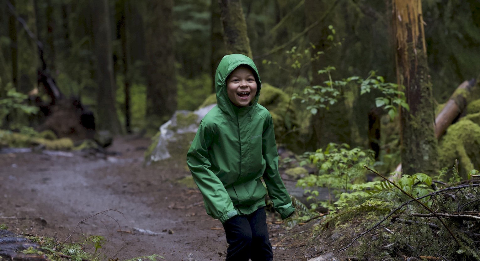 Child splashing in puddles in the forest