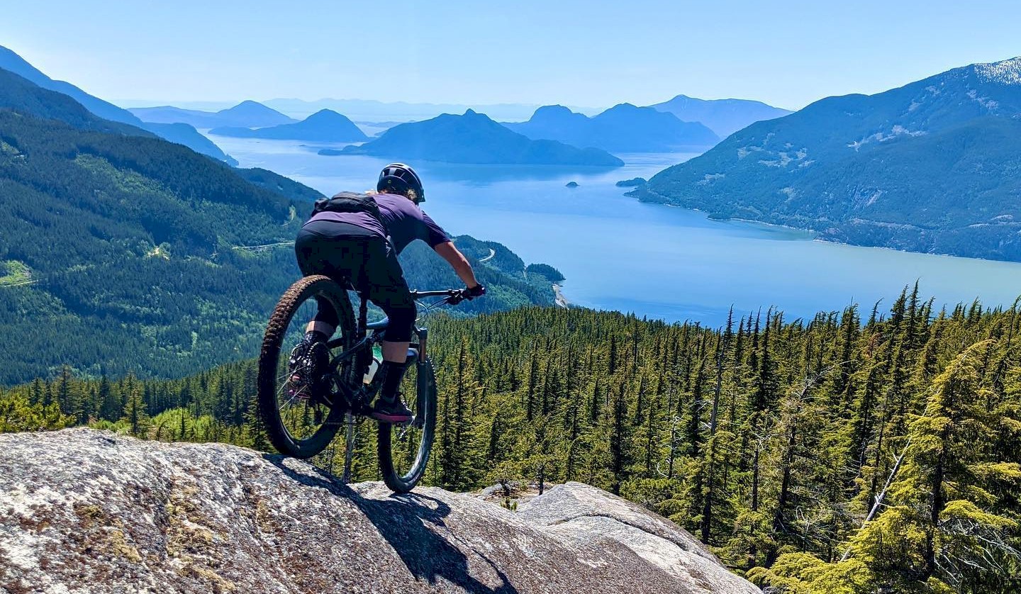Woman riding a granite slab with a view of Howe Sound