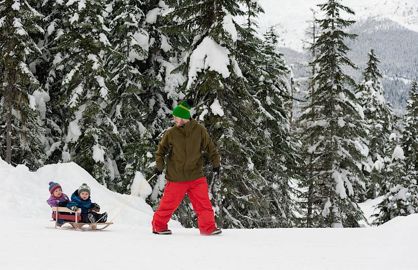 Dad pulling kids on a toboggan on a snowy day