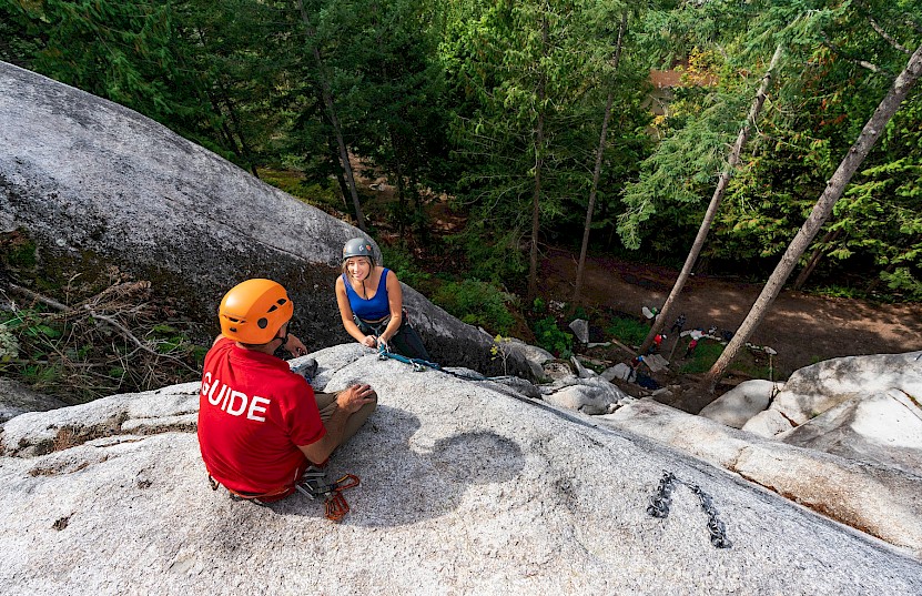 Guide at the top of a Squamish climbing crag helping their client