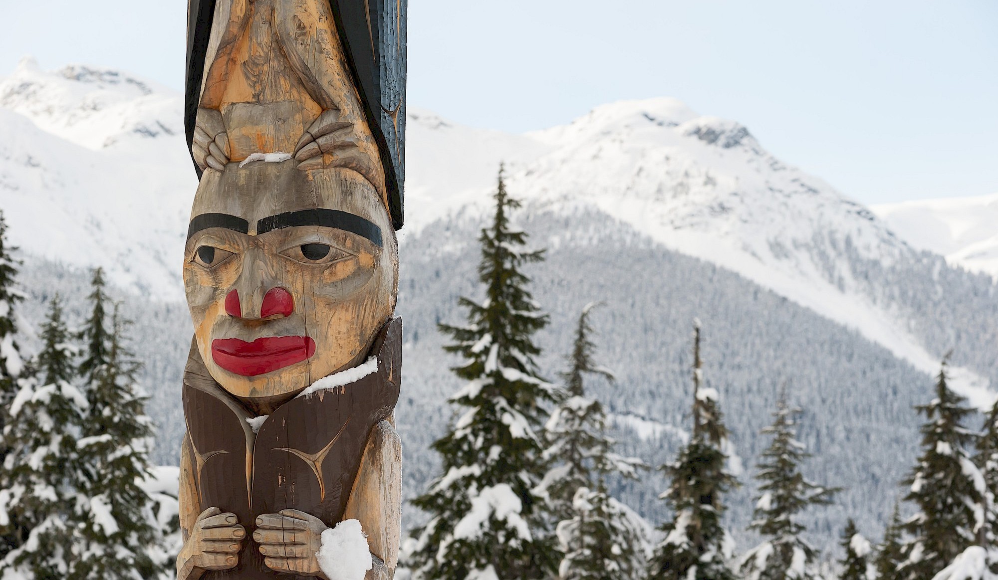 Totem pole with snowcapped mountains behind
