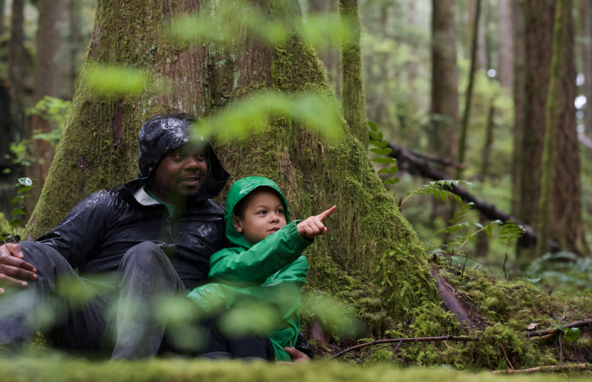 Father and son in the forest looking at an object outside of the frame