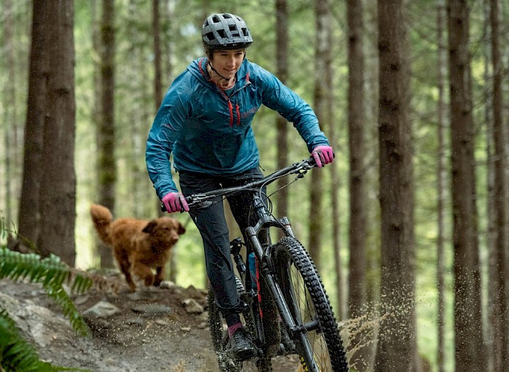 Woman on bike on a bike trail followed by a dog