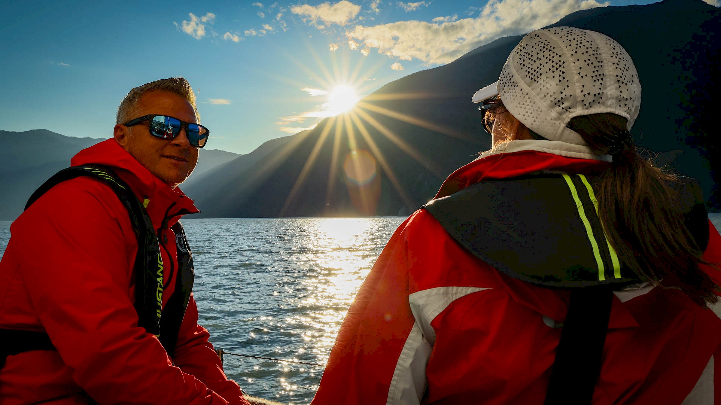 Man and woman on a sunny day on the water with mountain backdrop