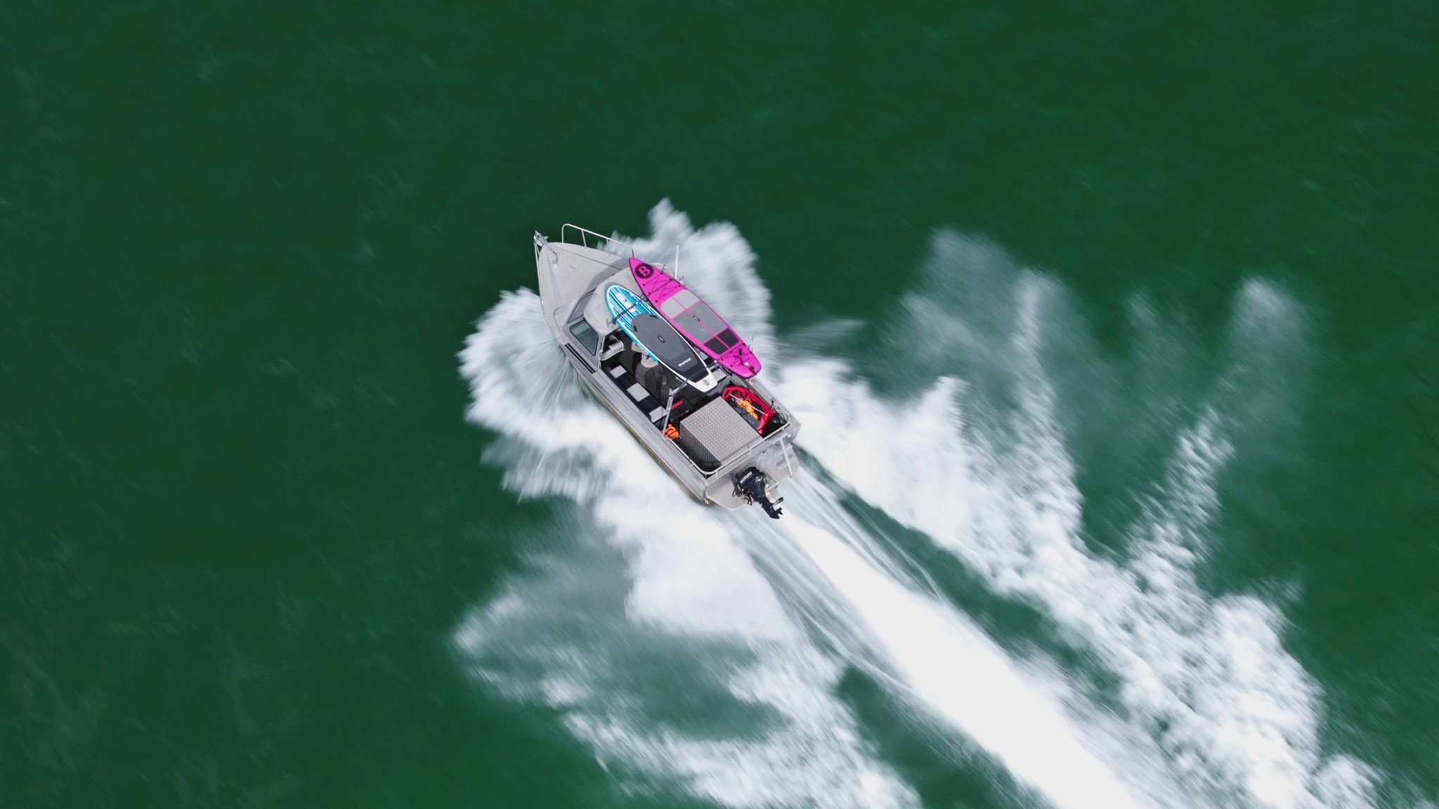 Shot from above of a boat with two paddle boards moving through the water of the Howe Sound